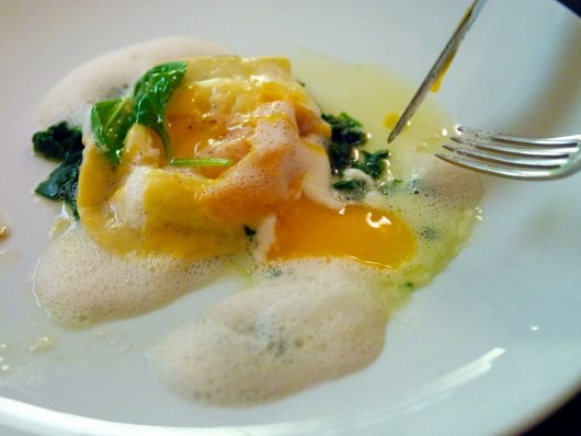 Angeschnittener Raviolon mit Schaffrischkäse, Blattspinat, Mimolette und ausrinnendem Eigelb Angeschnittener Raviolon mit Schaffrischkäse, Blattspinat, Mimolette und ausrinnendem Eigelb