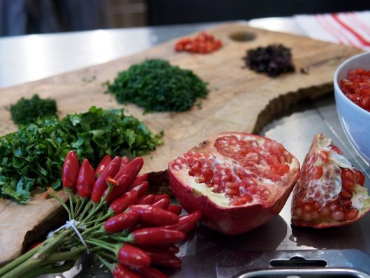 Chili, Granatapfel, Koriander, Petersilie und weitere Gewürze auf einem Holzbrett Chili, Granatapfel, Koriander, Petersilie und weitere Gewürze auf einem Holzbrett