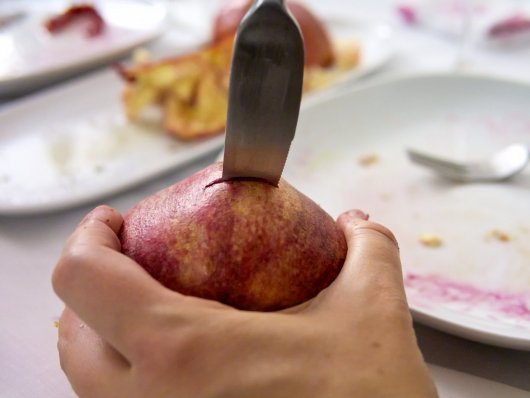 Ein Granatapfel wird angestochen Ein Granatapfel wird mit einem Messer zerteilt.
