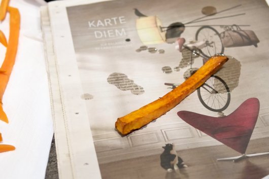 Probe-Süßkartoffel-Pommes-Frites Der Süßkartoffel-Probe-Pommes-Frites auf einer Zeitungsseite