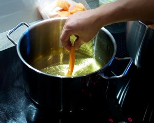 Probexemplar der Süßkartoffel-Pommes-Frites Ein Probe-Süßkartoffel-Pommes-Frites wird fritiert