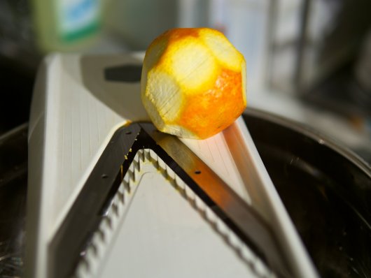 Die Schale einer Orange wird mit dem V-Hobel in feine Streifen geschnitten