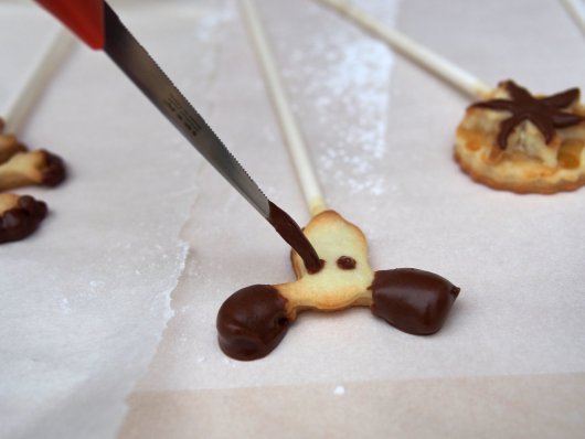 Keks-Pops werden mit Schokolade verziert