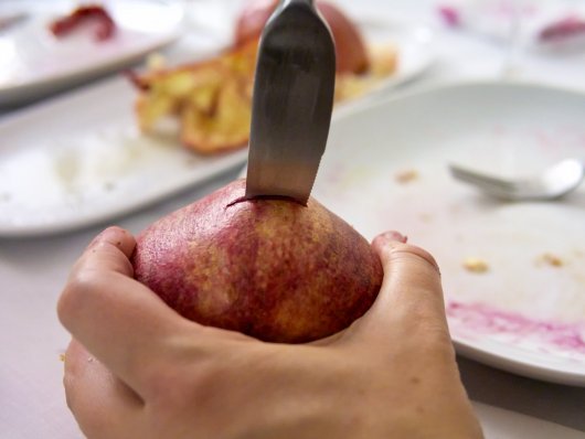 Ein Granatapfel wird mit einem Messer zerteilt.