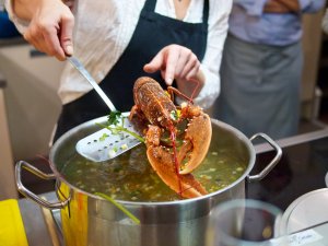 Gekochter Hummer Ein gekochter Hummer wird aus dem Kochtopf gehoben