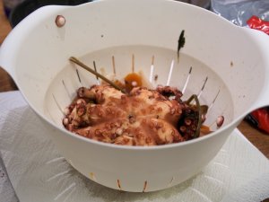 Gegarter Pulpo Ein gekochter Pulpo und verschiedene Gemüsereste in einem Plastiksieb