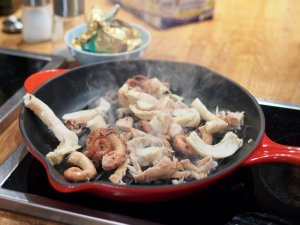 Oktopusarme in einer Gußeisenpfanne Oktopusarme werden in einer Gußeisenpfanne gebraten