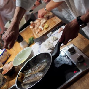 Zitrone zum Fisch Eine Zitrone wird über zwei gebratenen Fischfilets ausgequetscht.