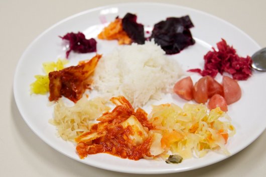 Teller mit Reis und verschiedenen vergoreren Gemüsen (Kimchi)