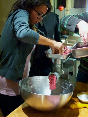 Körpereinsatz beim Wolfen Eine junge Frau wolft Schweinefleisch in eine große Schüssel