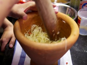 Salat aus roher Papaya Salat aus roher Papaya wird im Mörser gestampft.