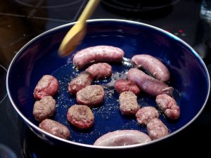 Bratwürste in der Pfanne Bratwürste und überschüssiges Wurstbrät in der Pfanne