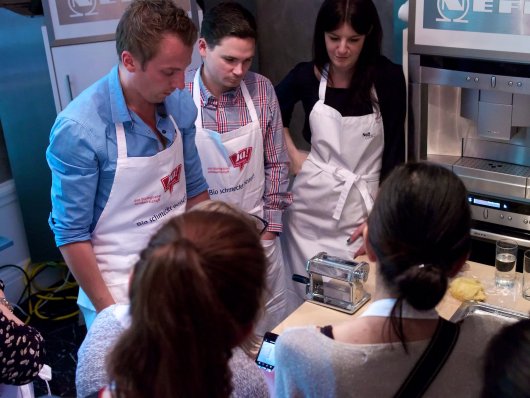 Foodblogger stehen um eine Pasta-Maschine mit Handkurbel