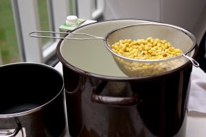 Sojabohnen in einem Sieb Sojabohnen tropfen in einem Sieb über einem großen Email-Topf ab