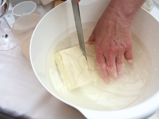 Selbst gemachter Tofu wird in einer mit Wasser gefüllten Schüssel geschnitten